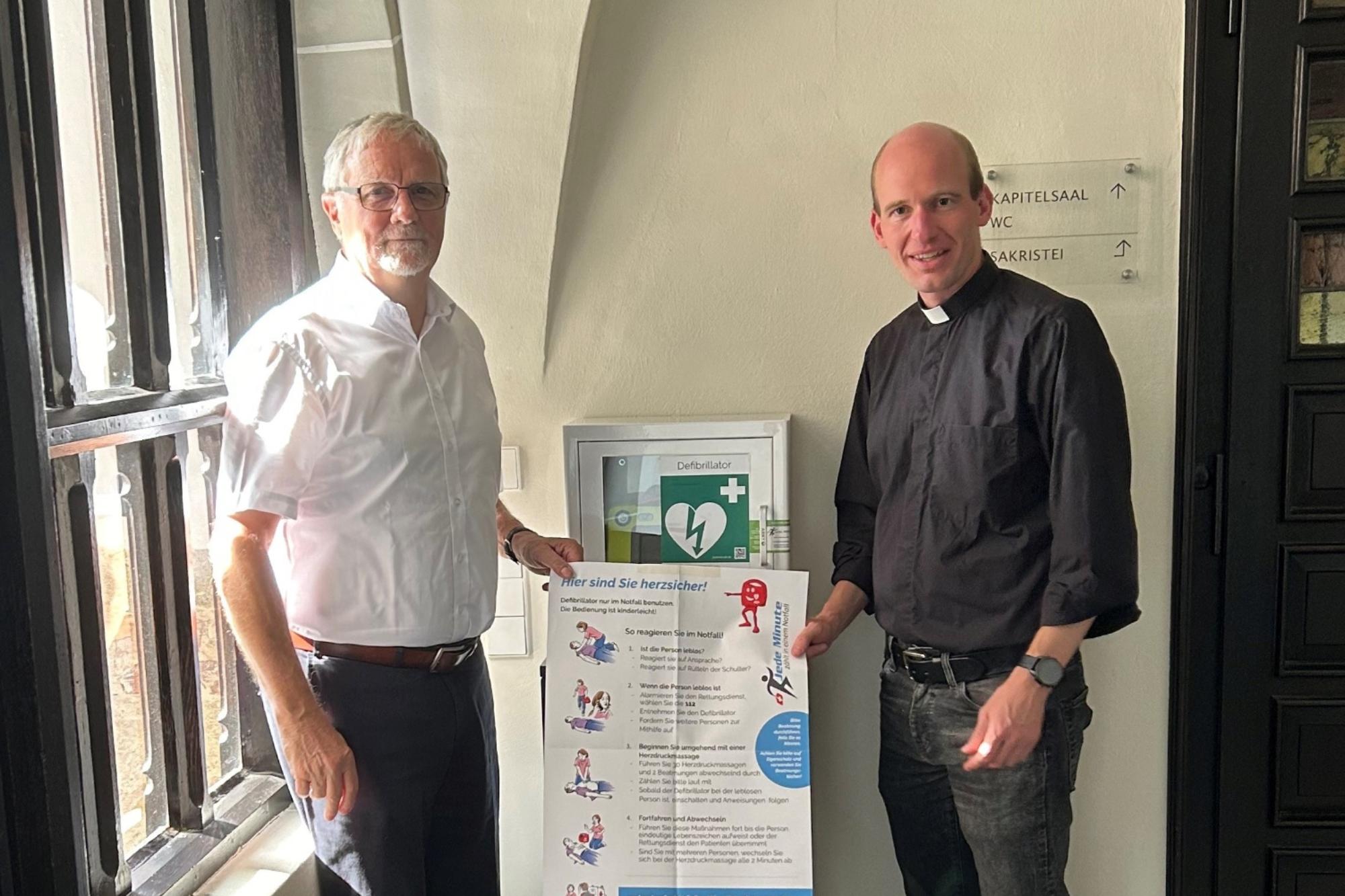 Ulrich Lipperheide, Vorsitzender des Münster-Bauvereins,  und Kaplan Dr. Chrisitan Jasper bei der Vorstellung des neuen Defibrillators