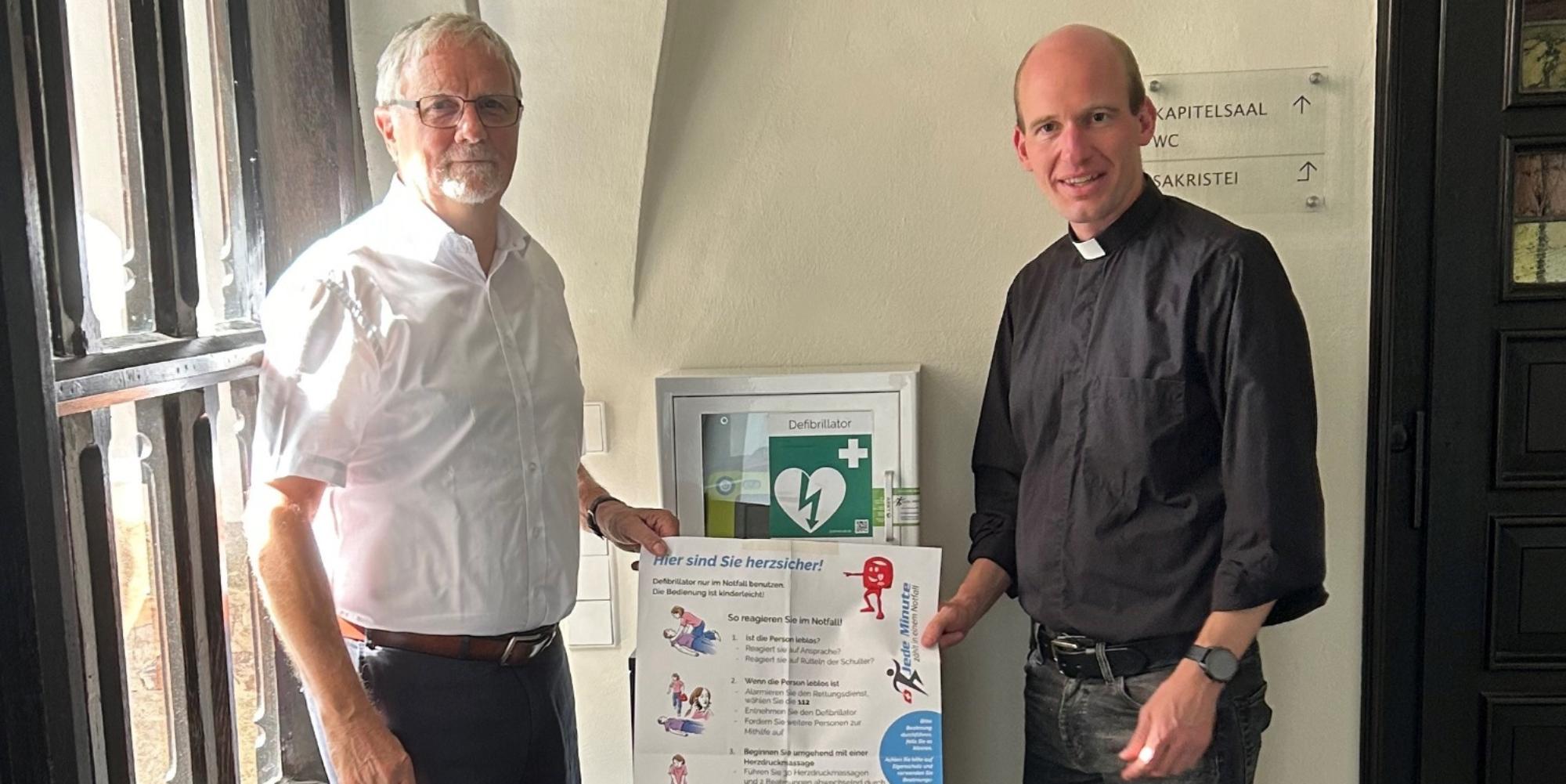Ulrich Lipperheide, Vorsitzender des Münster-Bauvereins, und Kaplan Dr. Chrisitan Jasper bei der Vorstellung des neuen Defibrillators